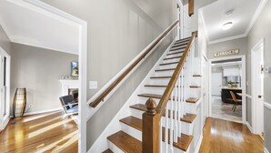 A staircase with wooden steps and white railings leading to a kitchen area. - NEW - Modern Cabin Oasis - 2 Acre Retreat! (Apex)