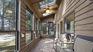 A covered patio area with large windows, a ceiling fan, and outdoor seating. - NEW - Modern Cabin Oasis - 2 Acre Retreat! (Apex)