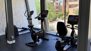 Ein Fitnessraum mit zwei Ergometer-Fahrrädern, einem Rudergerät und einem Laufband.