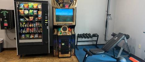 A gym with exercise equipment, a vending machine, and a treadmill.