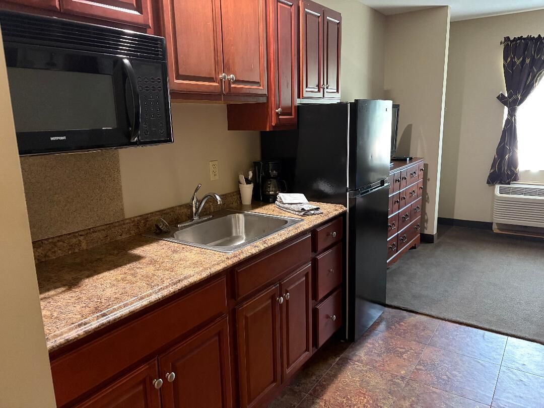 Cocina con microondas, refrigerador, pileta doble y muebles de madera.