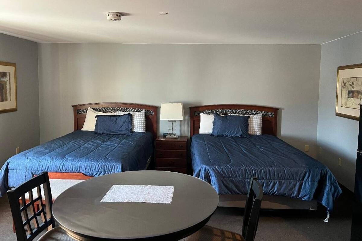A room with two beds, a round table, and a chair.