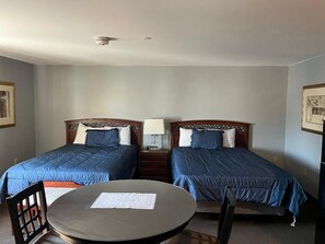 A room with two beds, a round table, and a chair.