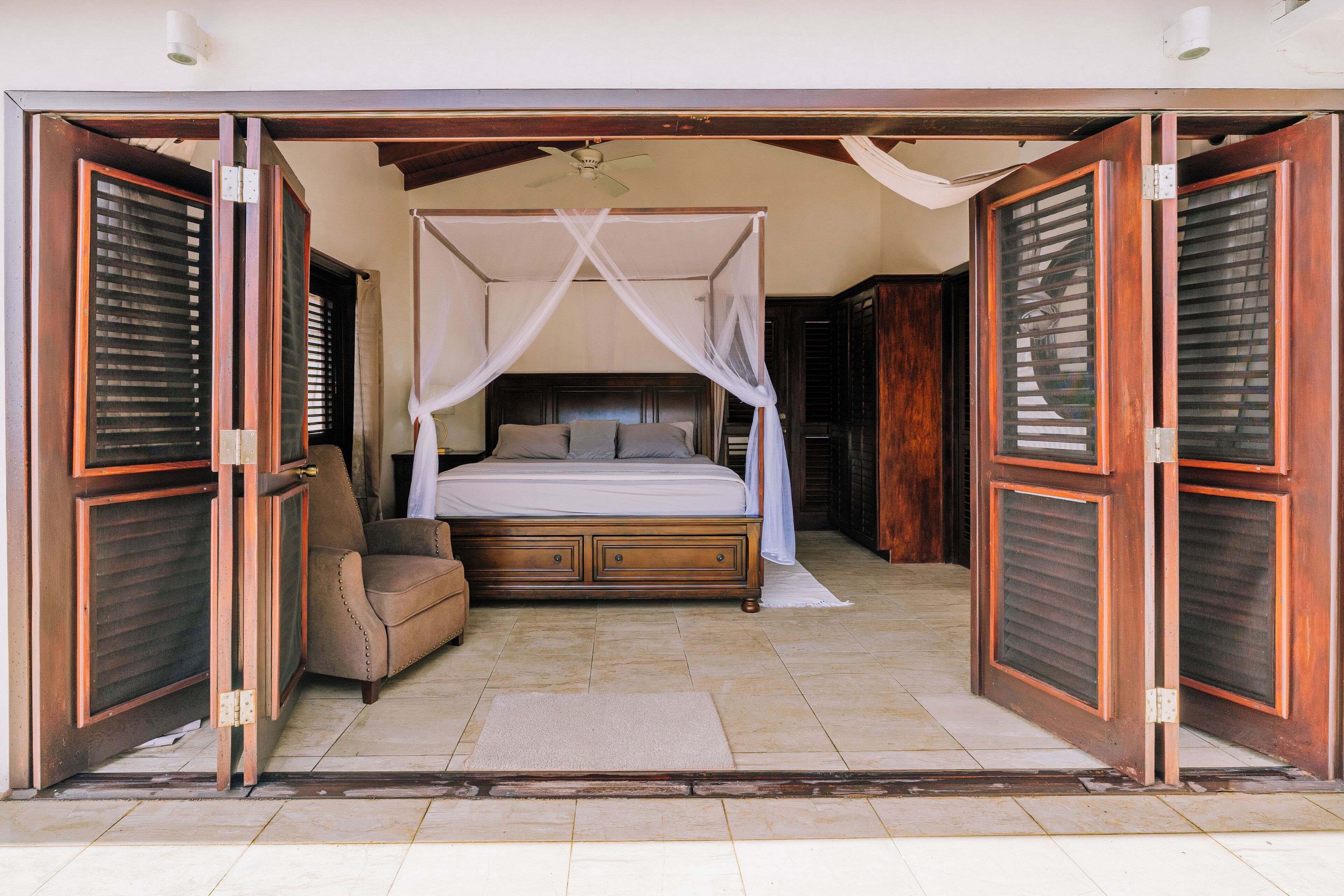 A bedroom with a four-poster bed, a nightstand, and a chair.