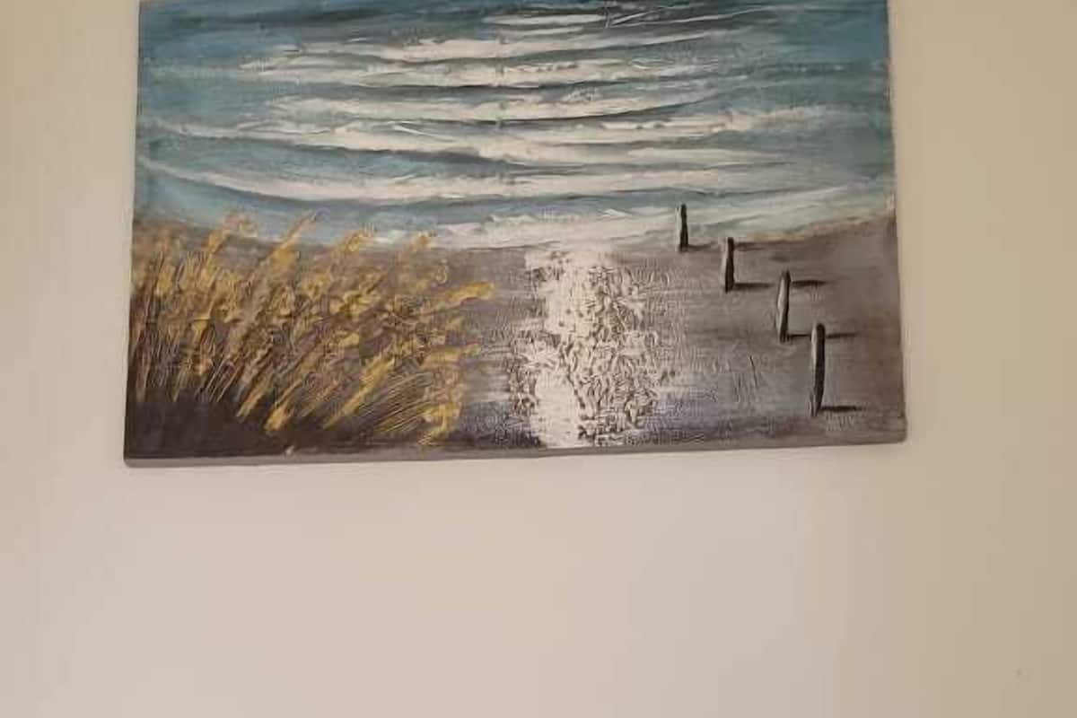 Un tableau représentant une scène de plage avec des vagues et un banc en bois.
