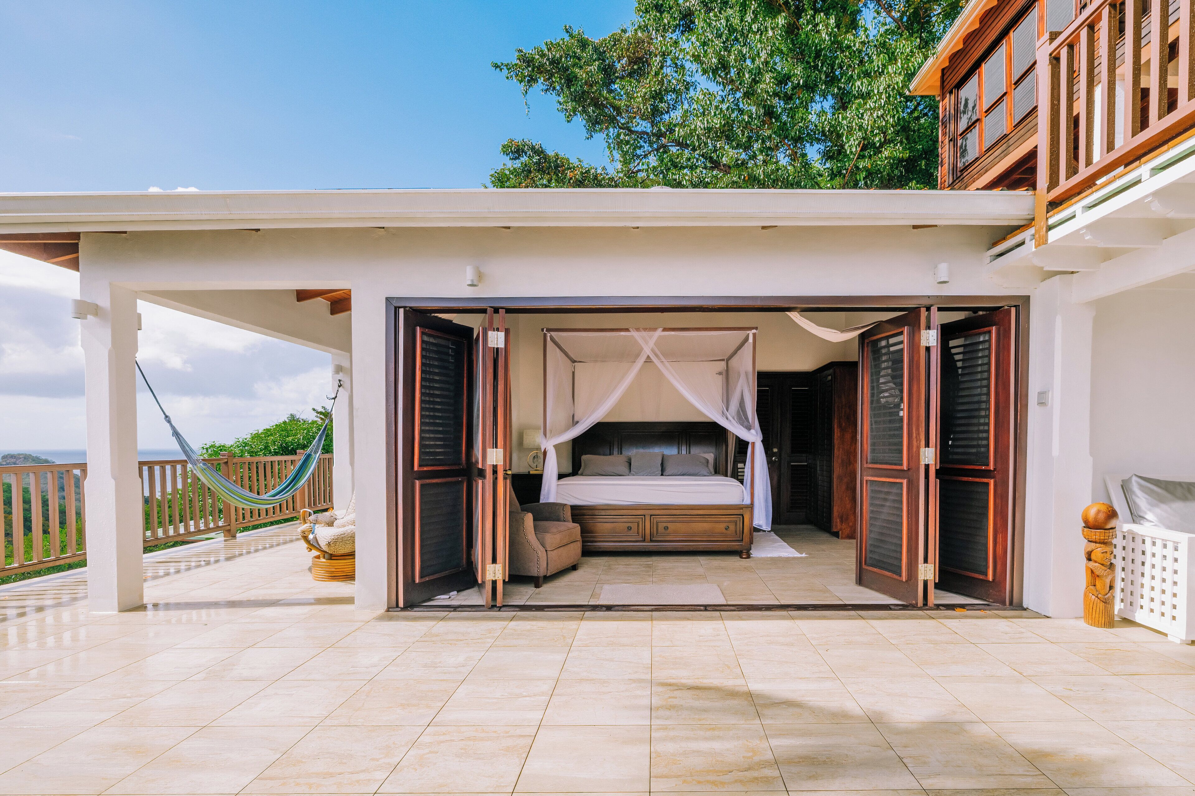 A bedroom with a canopy bed, a hammock, and a view of the outdoors.