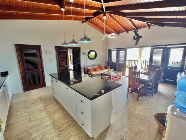 Una cocina amplia con una isla grande, vigas de techo de madera y un comedor con mesa y sillas.