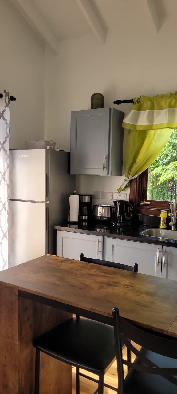 A compact kitchen with a refrigerator, a coffee maker, and a kettle on the counter.