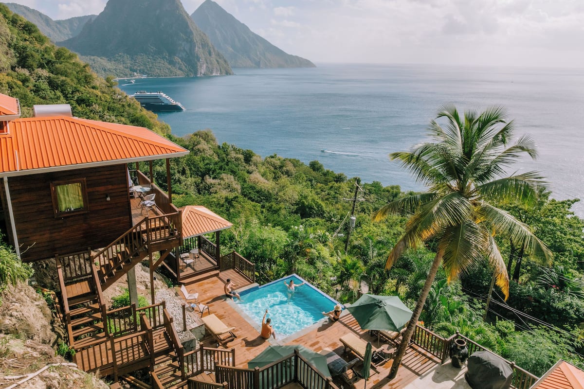 Une villa en bois dotée d’une piscine, offrant une vue imprenable sur un paysage tropical et la mer.
