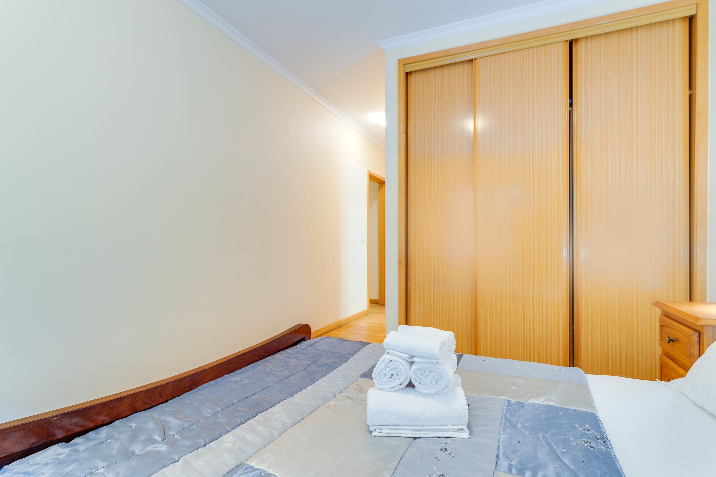 Een hotelkamer met een bed, een houten garderobe en een nachtkastje.