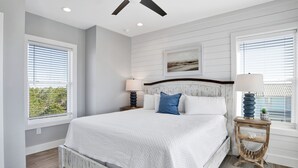 A bedroom with a bed, two bedside tables, a ceiling fan, and a window with blinds. - Luxury Coastal Escape | Heated Pool | Golf Cart Included (Gulf Shores)
