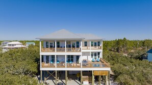 A two-story beachfront house with multiple balconies, large windows, and a wooden deck. - Luxury Coastal Escape | Heated Pool | Golf Cart Included (Gulf Shores)