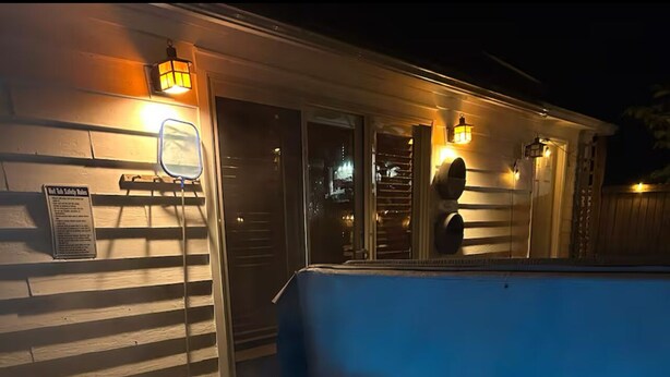 Een hottub met blauwe verlichting, een veiligheidssign en een houten terras.