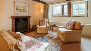 A cozy living room with a fireplace, two armchairs, a sofa, and a patterned rug. - Townend Farmhouse - Watermillock, Ullswater (Watermillock)