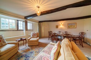 Una sala de estar acogedora con un sofá, un sillón y una mesa de comedor preparada para seis personas.