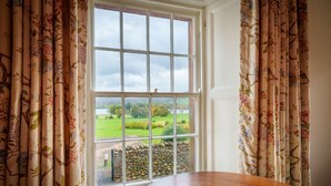 A room with a large window, a wooden table, and floral curtains. - Townend Farmhouse - Watermillock, Ullswater (Watermillock)