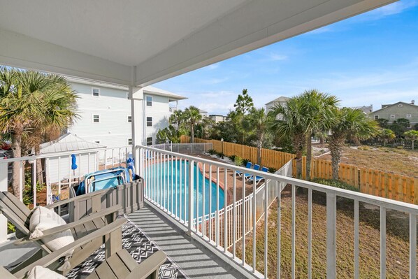 A balcony with a pool, white railing, and a view of the surrounding area including houses and palm trees. - 🐟30A Close to Beach-Snowbird Friendly-Beachside Villas-A Sandy Carol (Santa Rosa Beach)