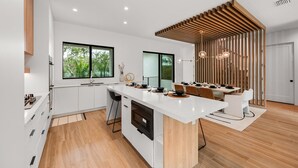 A modern kitchen with a large island, white cabinetry, and a wooden ceiling design. - Brand New home with Incredible Rooftop Deck and Pool! - Just Breathe (Anna Maria)