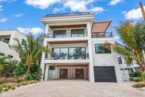 Una casa moderna de dos pisos con entrada porticada, ventanas amplias y un balcón.