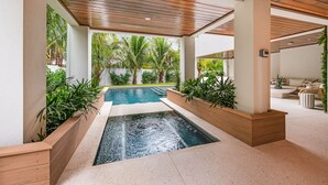 A modern indoor pool area with wooden beams, a clear view of the pool, and surrounding greenery. - Brand New home with Incredible Rooftop Deck and Pool! - Just Breathe (Anna Maria)