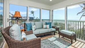 Un balcon agrémenté de meubles en osier, d’un tapis à motifs et offrant une vue sur la plage.