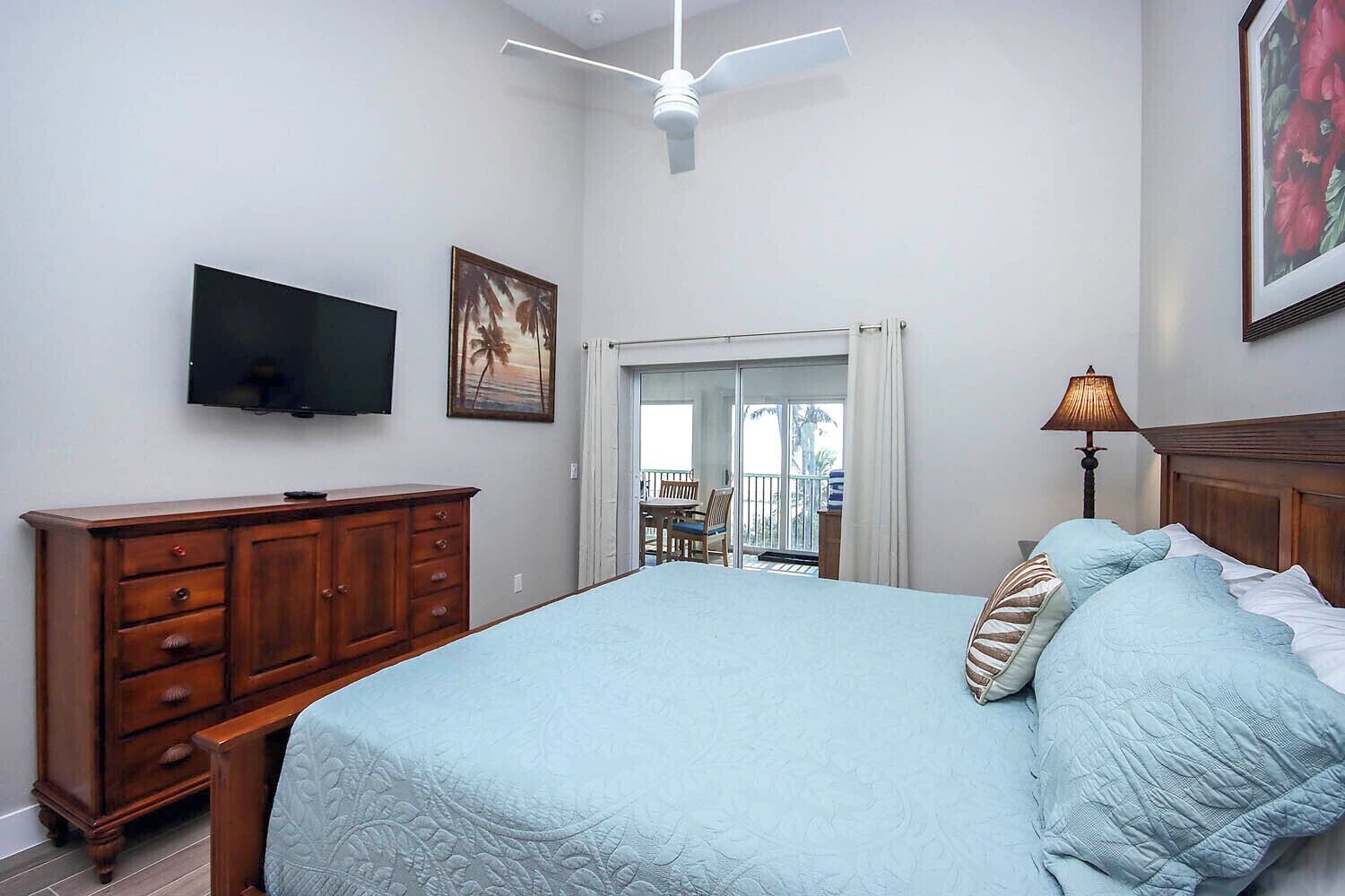 Un dormitorio con cama, cómoda de madera, televisor y ventilador de techo.