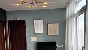 A modern living room with a sofa, a flat-screen TV, a coffee table, and a ceiling light fixture. - Central & Spacious Penthouse w/ 1BR + City View (L-Imsida)