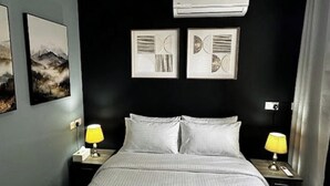 A neatly made bed with a striped bedspread, two bedside tables with lamps, and framed artwork on the wall. - Central & Spacious Penthouse w/ 1BR + City View (L-Imsida)