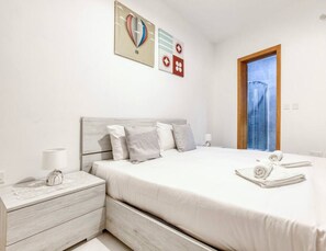 A neatly arranged bedroom with a bed, bedside tables, a lamp, and a window.
