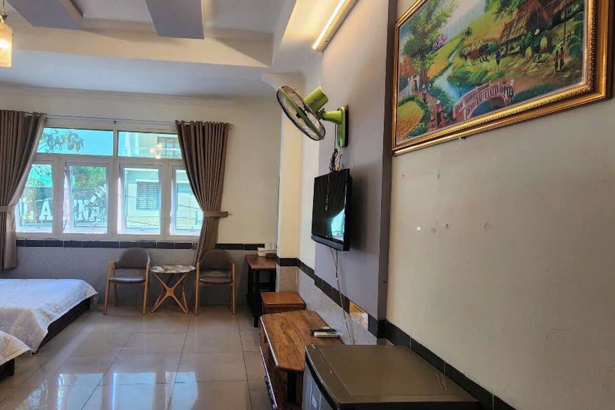 Habitación de hotel con dos camas, un escritorio, una silla, un televisor y un cuadro en la pared.