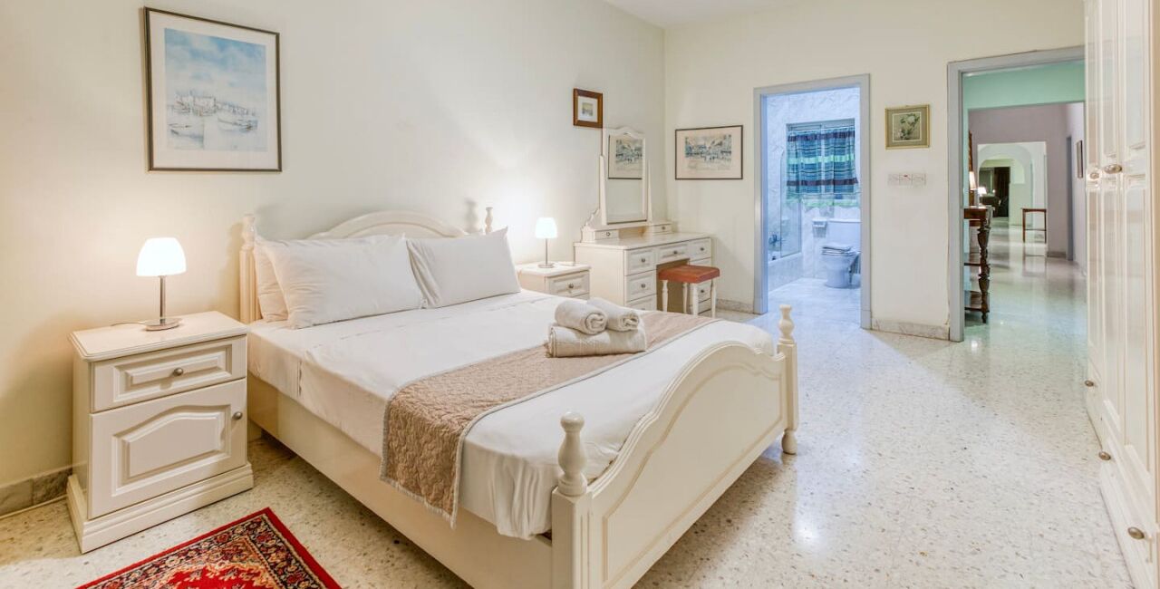 A bedroom with a bed, bedside tables, a nightstand, a dresser, and a mirror.