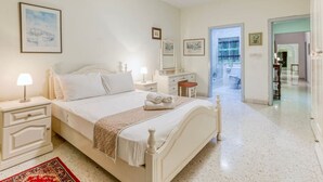 A bedroom with a bed, bedside tables, a nightstand, a dresser, and a mirror.