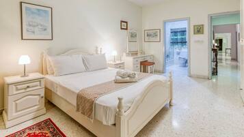 A bedroom with a bed, bedside tables, a nightstand, a dresser, and a mirror.