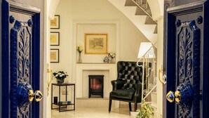 Una entrada imponente con candelabro, chimenea y sillón de cuero negro.