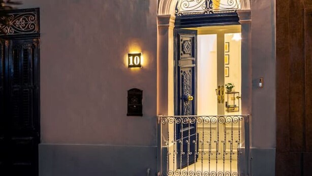 Un bâtiment doté d’un balcon, d’une porte surmontée d’un arc décoratif et d’un luminaire placé au-dessus de la porte.