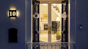 Une entrée imposante, agrémentée d’un portail en métal ouvragé, d’une enseigne lumineuse et d’un intérieur visible, avec une cheminée et des meubles.