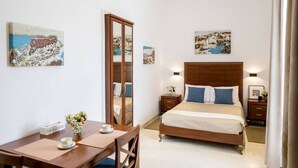 Une chambre d’hôtel comprenant un lit, des tables de chevet, un bureau avec une chaise et des œuvres d’art accrochées aux murs.