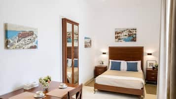 Habitació d'hotel amb llit, taules de nit, escriptori i cadira, i obra d'art a les parets.