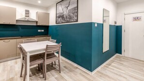 Une cuisine moderne avec une table et des chaises, un grand miroir et un mur d’accent bleu.