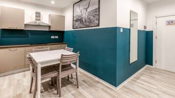 A modern kitchen with a dining table and chairs, a large mirror, and a blue accent wall.