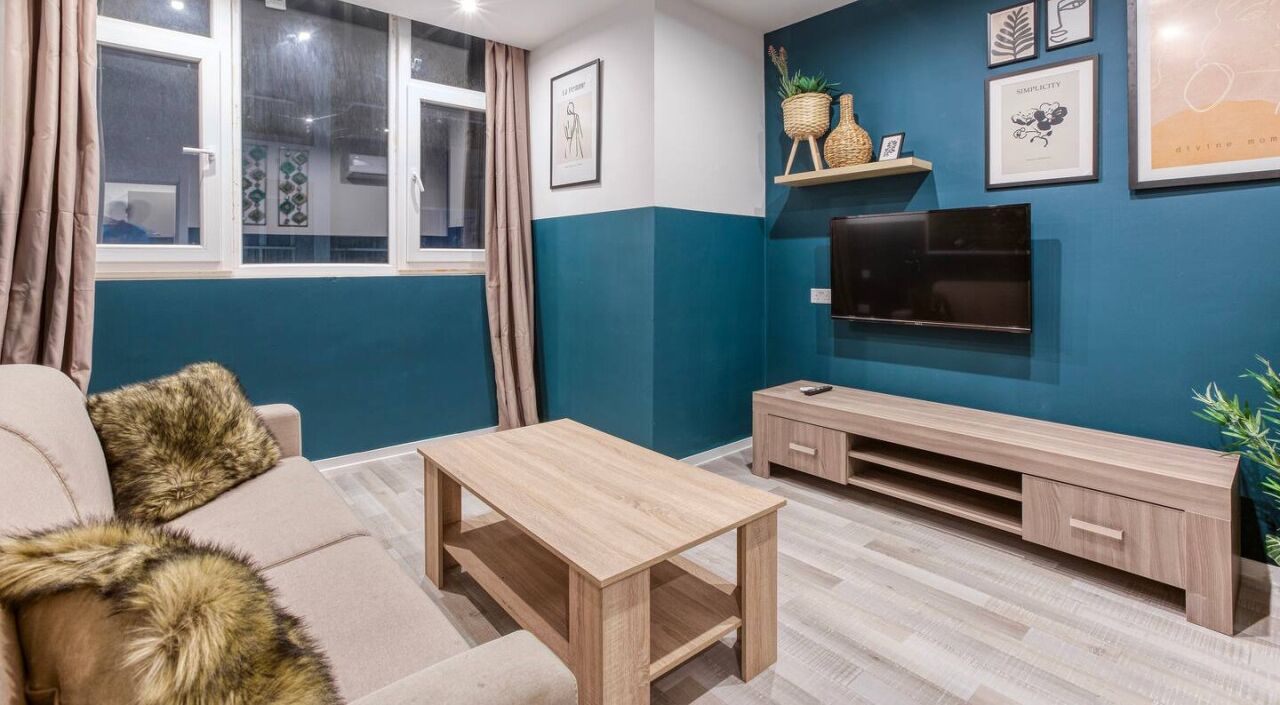 A living room with a sofa, a coffee table, a TV, and a TV stand.