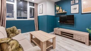 A living room with a sofa, a coffee table, a TV, and a TV stand.