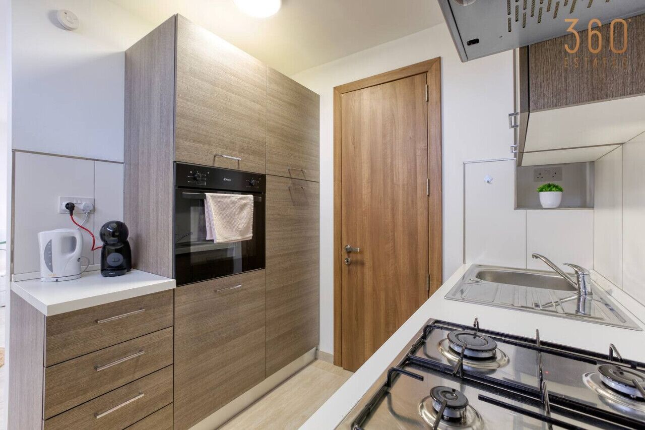 A modern kitchen with a built-in oven, a coffee maker, and a gas stove.