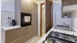 A modern kitchen with a built-in oven, a coffee maker, and a stove. - A lovely, studio penthouse with private balcony (San Ġiljan)