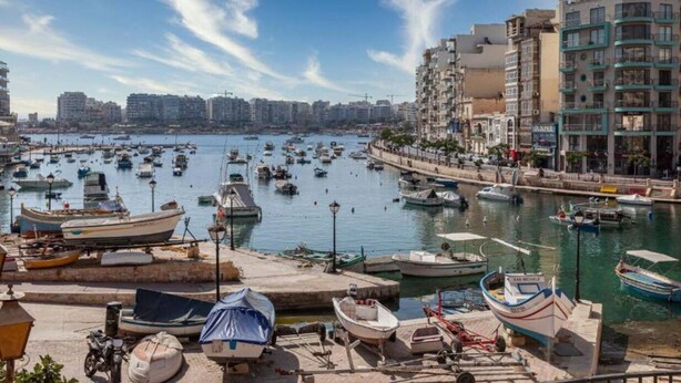 A marina with numerous boats docked, surrounded by residential buildings and a clear sky. - A lovely, studio penthouse with private balcony (San Ġiljan)
