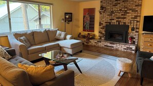 Una sala de estar con un sofá modular, una mesa de centro de vidrio, una chimenea y un televisor.