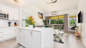 A modern kitchen with white cabinetry, a built-in microwave, and a central island with a marble countertop.