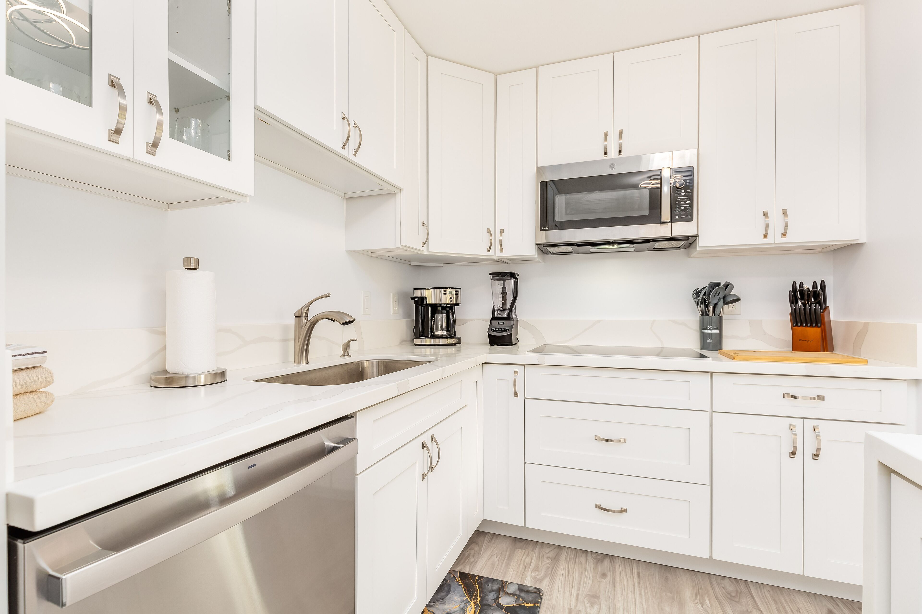 A modern kitchen with white cabinetry, stainless steel appliances, and a built-in microwave.