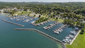 An aerial view of a marina with numerous boats docked, surrounded by residential areas and greenery.
