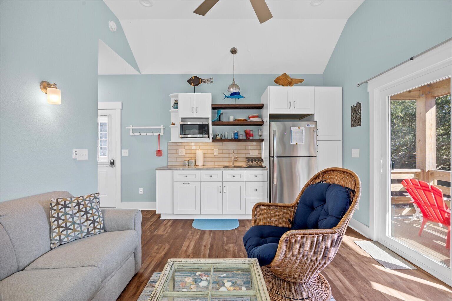 A compact living space with a kitchenette, a dining area, and a seating area with a wicker chair and a sofa.